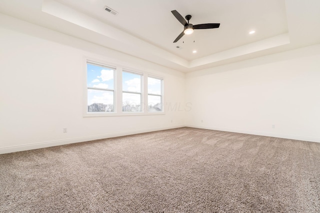 spare room with baseboards, ceiling fan, carpet floors, and a tray ceiling