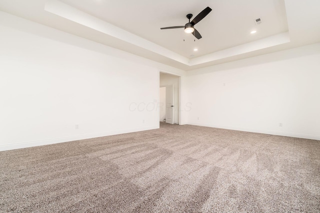 carpeted empty room featuring recessed lighting, ceiling fan, baseboards, visible vents, and a raised ceiling