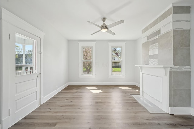 unfurnished living room featuring a ceiling fan, a healthy amount of sunlight, and light wood finished floors
