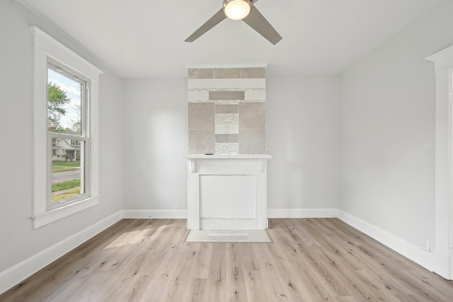 unfurnished living room featuring ceiling fan, baseboards, and light wood-style floors