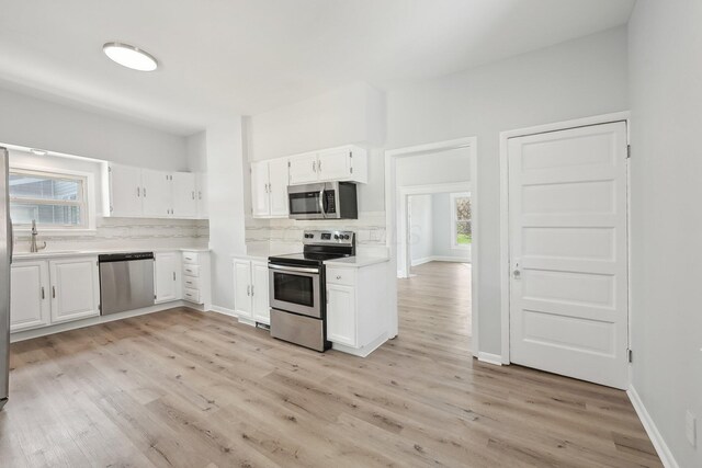 kitchen with light wood-style floors, appliances with stainless steel finishes, decorative backsplash, and light countertops