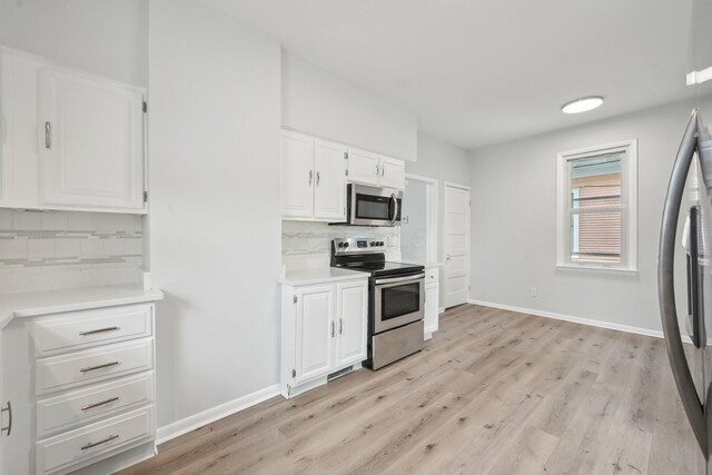 kitchen featuring stainless steel appliances, decorative backsplash, light wood-style flooring, and white cabinets