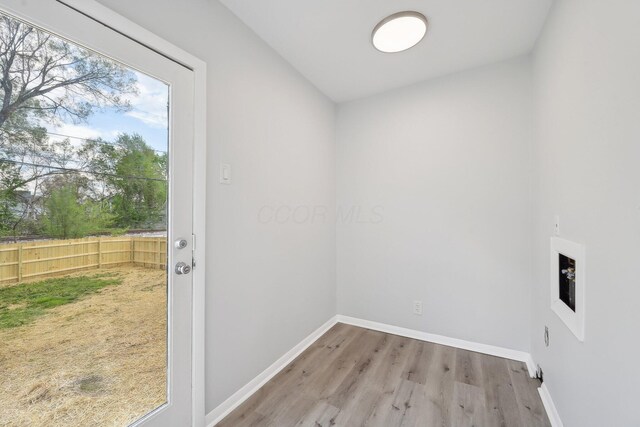 clothes washing area featuring wood finished floors and baseboards