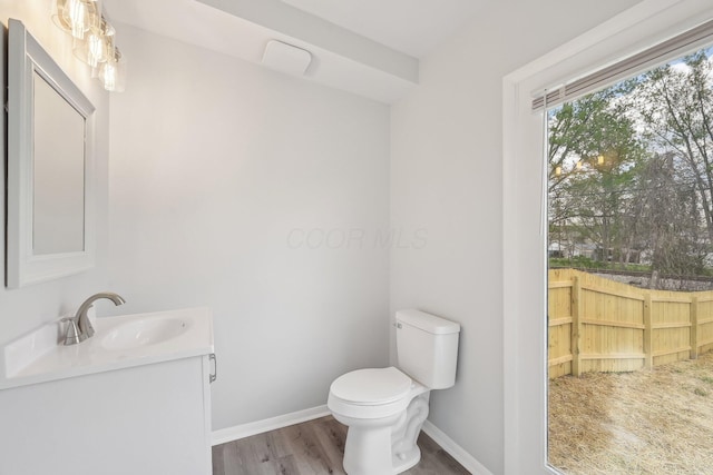 bathroom featuring wood finished floors, toilet, vanity, and baseboards