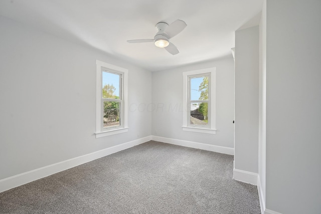 spare room featuring dark carpet, ceiling fan, and baseboards