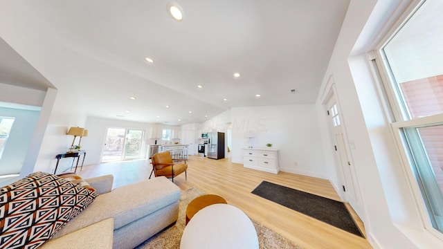 living room with recessed lighting, baseboards, lofted ceiling, and light wood-style flooring