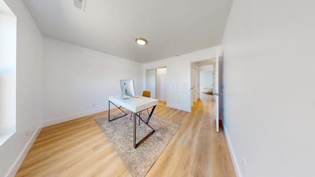 home office featuring light wood-type flooring, visible vents, and baseboards