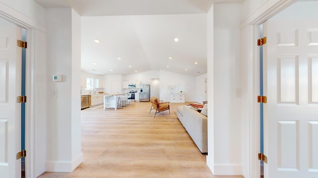 corridor featuring recessed lighting, lofted ceiling, baseboards, and light wood-style flooring
