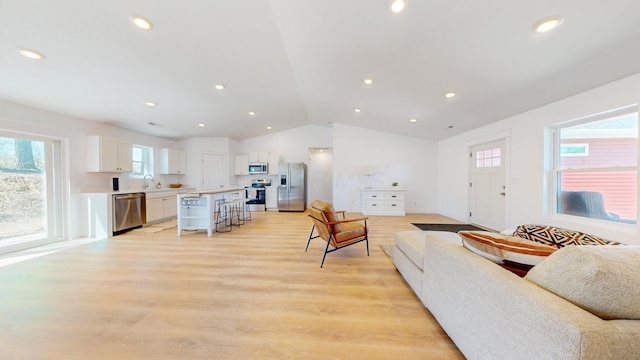living area with recessed lighting, lofted ceiling, and light wood-style flooring