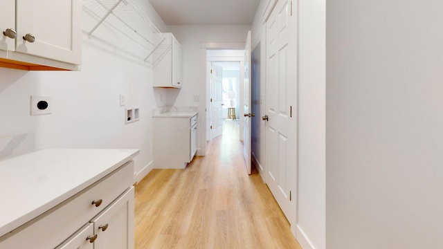 laundry area with electric dryer hookup, cabinet space, light wood finished floors, baseboards, and washer hookup