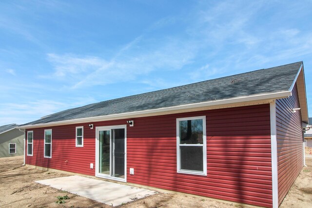 back of property with a shingled roof and a patio