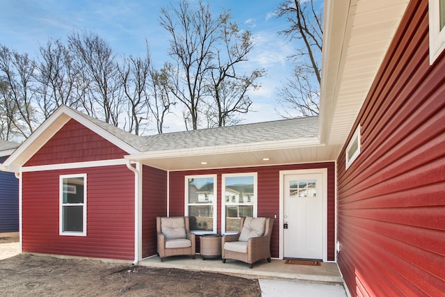view of exterior entry featuring roof with shingles