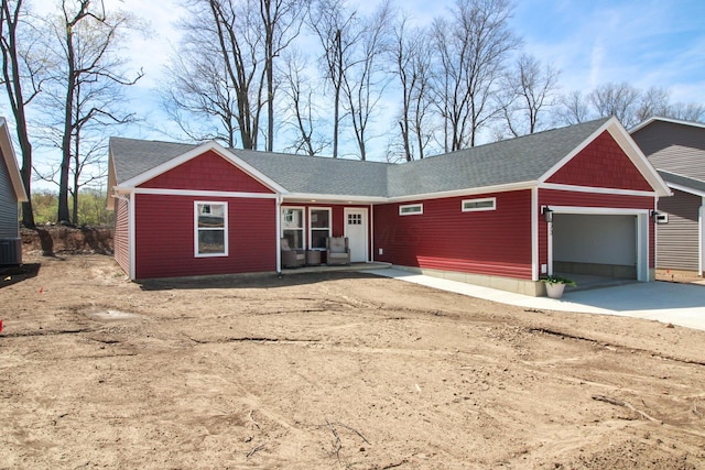 ranch-style house featuring a shingled roof, concrete driveway, central AC, and a garage