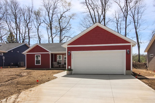 single story home with concrete driveway, an attached garage, and central AC