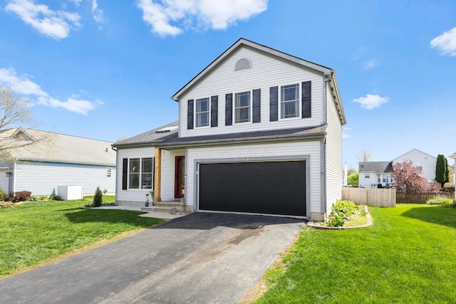 traditional-style home featuring a garage, fence, a front lawn, and aphalt driveway