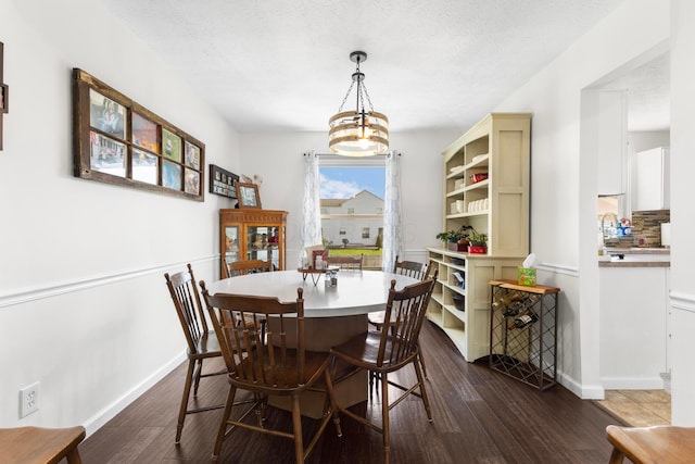 dining space with baseboards, a textured ceiling, dark wood-style flooring, and a chandelier