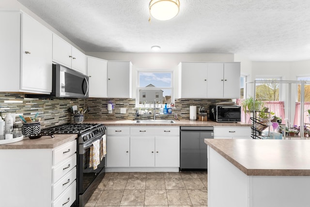 kitchen with a sink, backsplash, stainless steel appliances, and white cabinetry