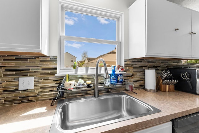 kitchen with white cabinetry, decorative backsplash, and a sink