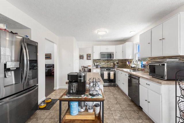 kitchen featuring appliances with stainless steel finishes, a sink, a textured ceiling, white cabinetry, and decorative backsplash