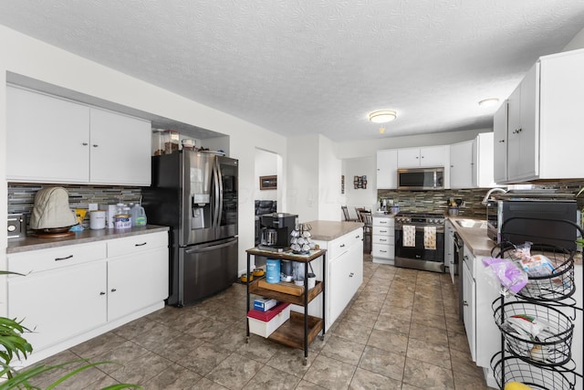 kitchen featuring appliances with stainless steel finishes, white cabinets, backsplash, and a textured ceiling