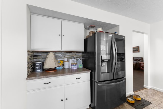 kitchen featuring dark countertops, decorative backsplash, stainless steel refrigerator with ice dispenser, and white cabinets