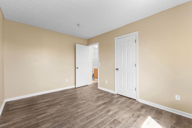 unfurnished bedroom with baseboards and dark wood-style flooring