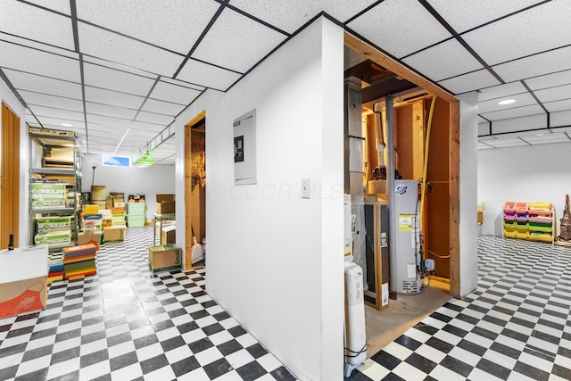finished basement featuring tile patterned floors, a drop ceiling, electric panel, and gas water heater