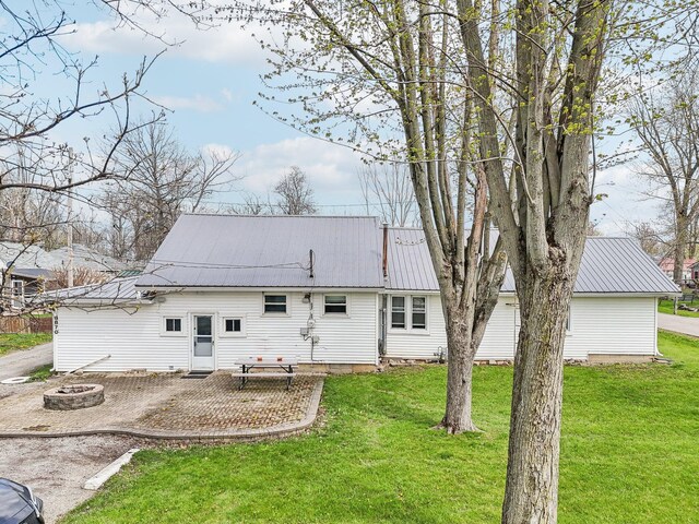 8870 College St, Lakeview, OH 43331 - rear view of house featuring a fire pit, a yard, a patio area, and metal roof