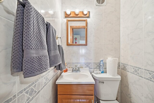 8870 College St, Lakeview, OH 43331 - half bathroom with decorative backsplash, vanity, tile walls, toilet, and visible vents