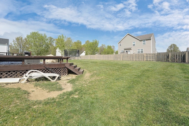 view of yard featuring a fenced backyard, a deck, and a trampoline