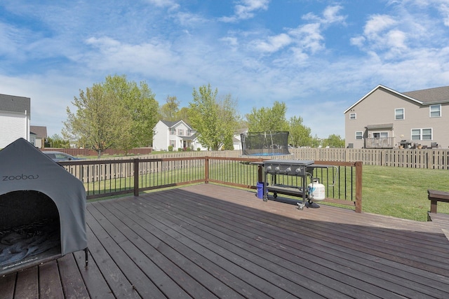 deck with a yard, a trampoline, a fenced backyard, and a residential view