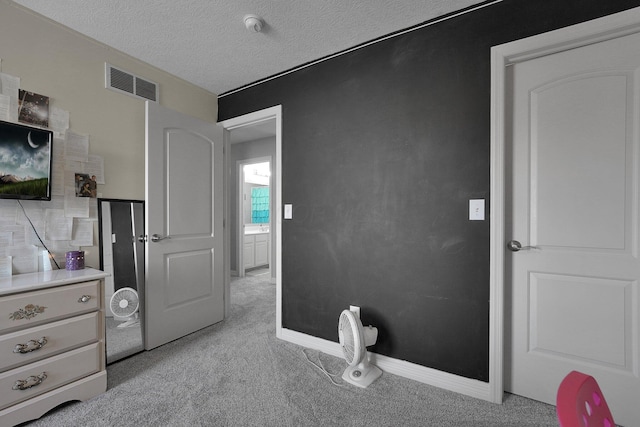 bedroom with light colored carpet, baseboards, a textured ceiling, and visible vents