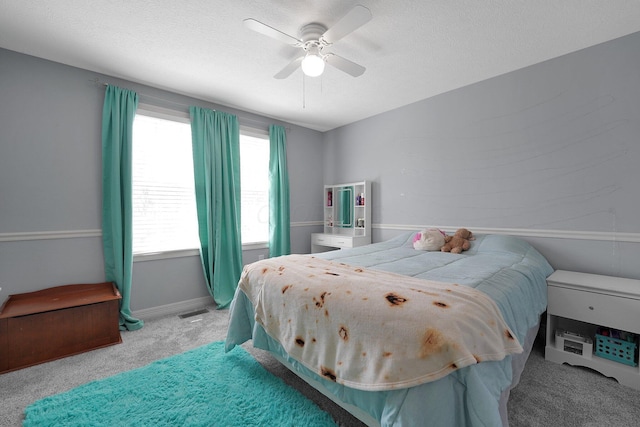 bedroom with visible vents, a ceiling fan, baseboards, a textured ceiling, and light colored carpet