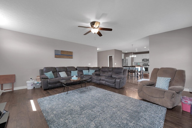 living room with baseboards, dark wood-style flooring, and ceiling fan with notable chandelier