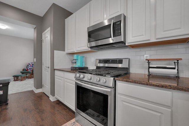 kitchen featuring dark stone counters, white cabinets, stainless steel appliances, and dark wood-style floors