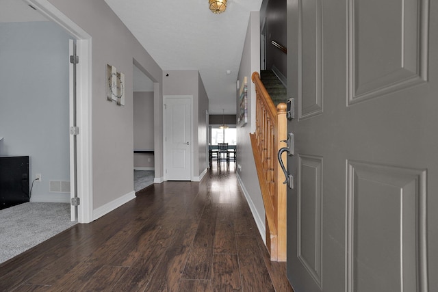 hallway with stairs, baseboards, visible vents, and dark wood-type flooring