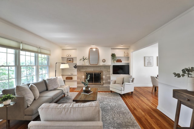living room with crown molding, dark wood-style flooring, and a stone fireplace