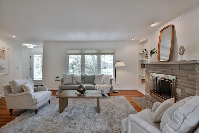 living room featuring recessed lighting, baseboards, a stone fireplace, and wood finished floors