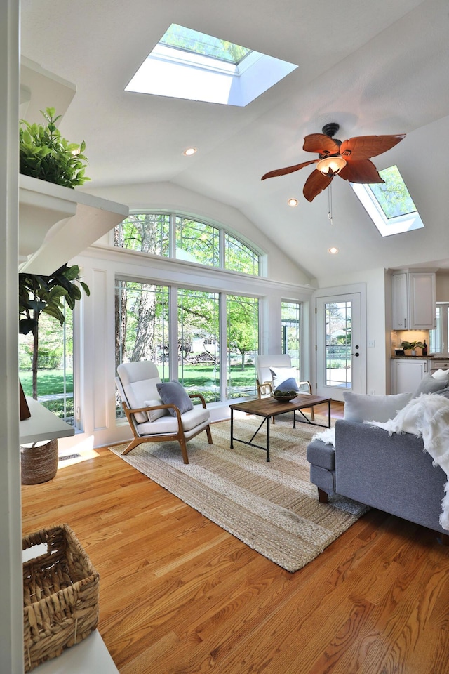 living area with recessed lighting, ceiling fan, wood finished floors, and vaulted ceiling with skylight