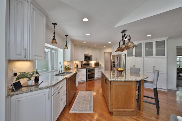 kitchen featuring a sink, a kitchen island, stainless steel appliances, and white cabinetry