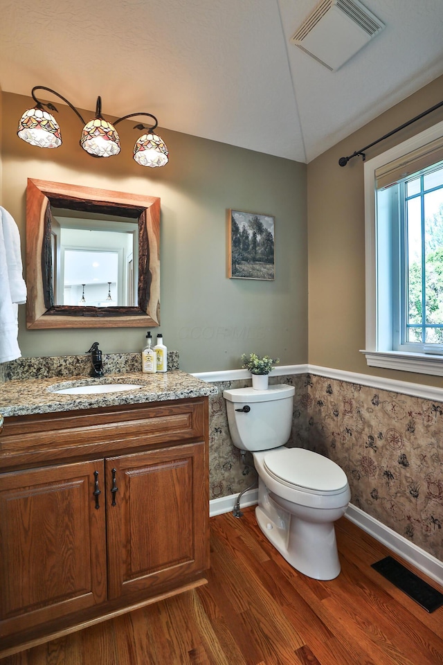 half bathroom featuring lofted ceiling, wood finished floors, and visible vents
