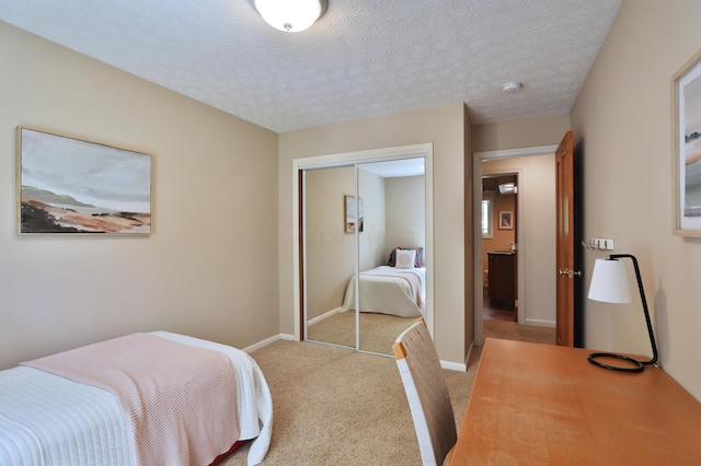 bedroom with light colored carpet, a textured ceiling, baseboards, and a closet