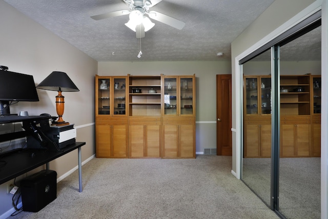 home office with carpet flooring, a ceiling fan, and a textured ceiling