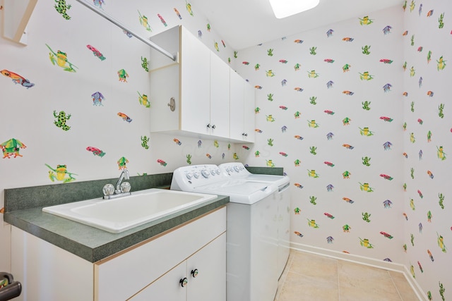 clothes washing area featuring washing machine and clothes dryer, a sink, wallpapered walls, baseboards, and cabinet space