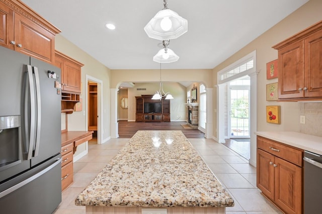 kitchen featuring arched walkways, stainless steel appliances, a kitchen island, open floor plan, and light tile patterned flooring