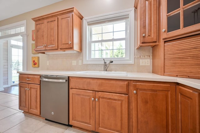 kitchen with light countertops, stainless steel dishwasher, backsplash, and a sink