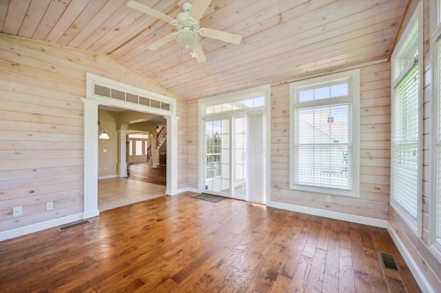 empty room with wood ceiling, wooden walls, visible vents, and vaulted ceiling
