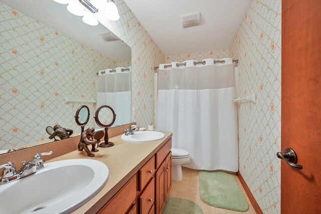 bathroom with tile patterned floors, toilet, double vanity, and a sink