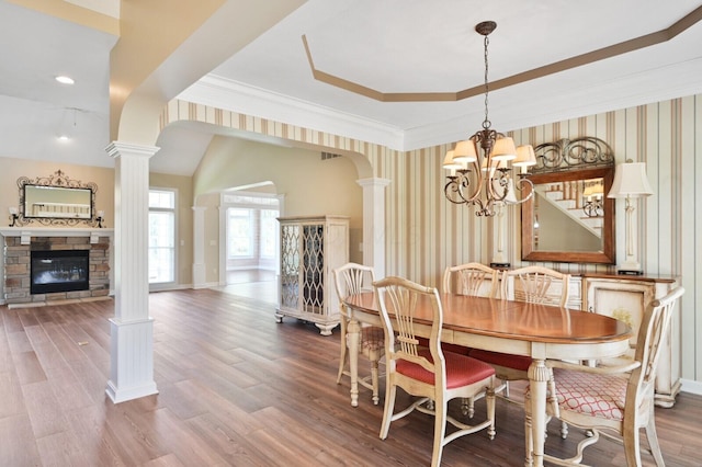 dining area featuring ornate columns, a chandelier, and wallpapered walls
