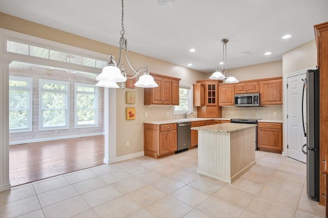 kitchen featuring glass insert cabinets, stainless steel appliances, a kitchen island, brown cabinets, and backsplash